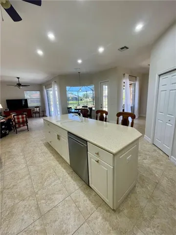 Kitchen featuring white cabinets, dishwasher, a center island, and sink