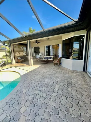 Rear view of house featuring outdoor lounge area, a patio, glass enclosure, and ceiling fan