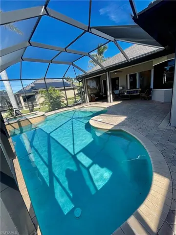 View of pool with glass enclosure, ceiling fan, an in ground hot tub, and a patio