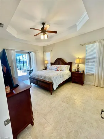 Bedroom with a tray ceiling, ceiling fan, and ornamental molding