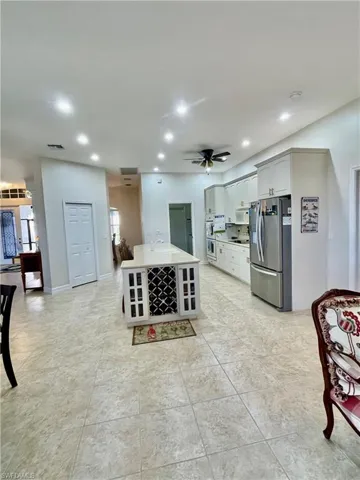 Kitchen featuring sink, ceiling fan, stainless steel fridge, an island with sink, and stovetop
