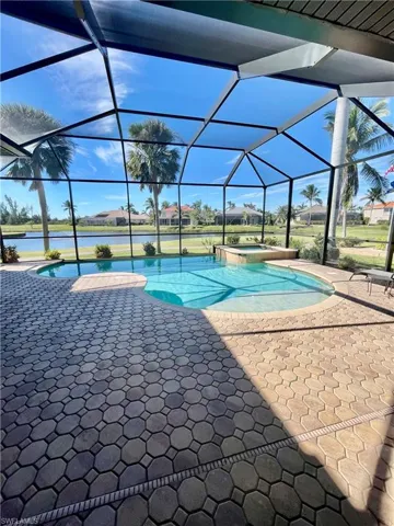 View of swimming pool with a lanai, a patio area, a water view, and an inground hot tub