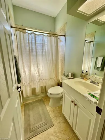 Full bathroom featuring tile patterned floors, shower / bath combo, toilet, and vanity