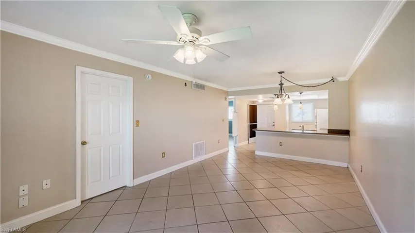 Unfurnished room with light tile patterned floors, crown molding, a ceiling fan, and a chandelier
