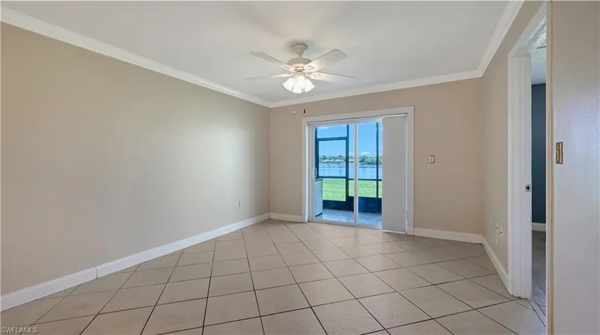 Unfurnished room with crown molding, a ceiling fan, light tile patterned floors, and a water view