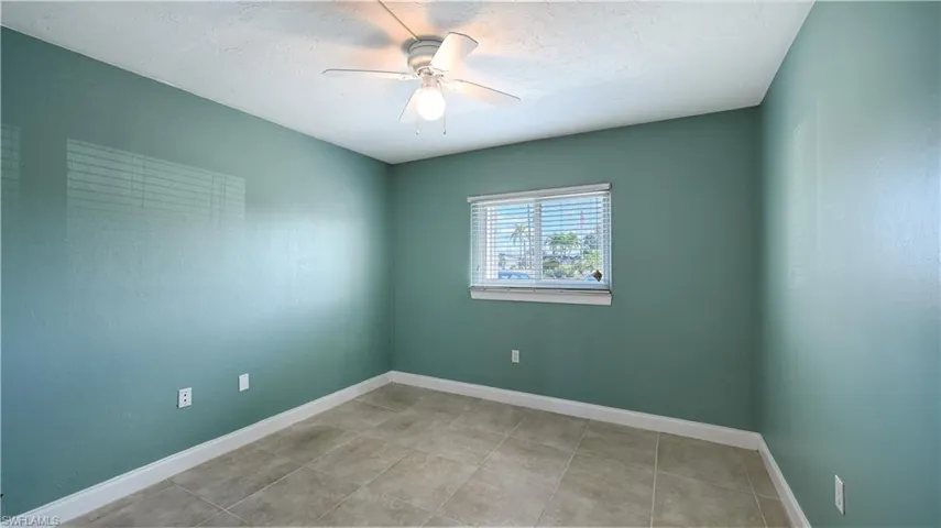 Empty room with ceiling fan and light tile patterned flooring