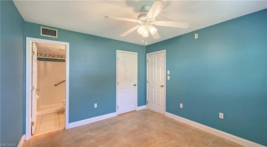 Unfurnished bedroom featuring a ceiling fan, ensuite bathroom, and tile patterned flooring