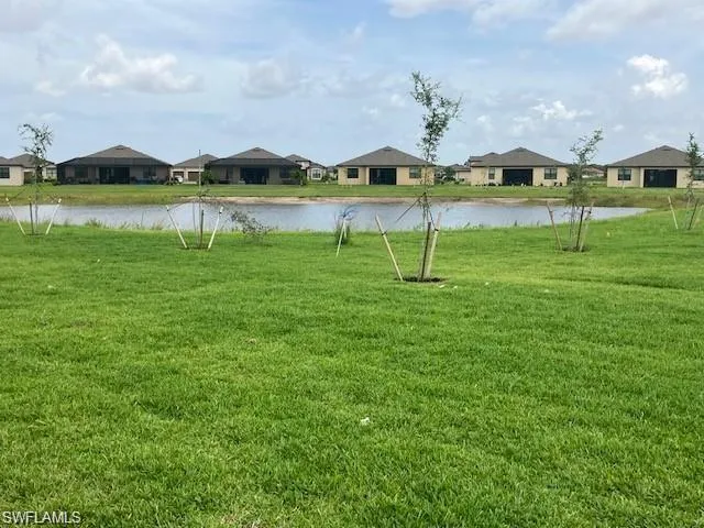 View of green lawn featuring a residential view and a water view