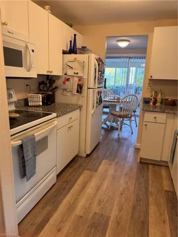 Kitchen featuring laminate flooring, granite countertops, soft close bottom cabinets, white kitchen appliances