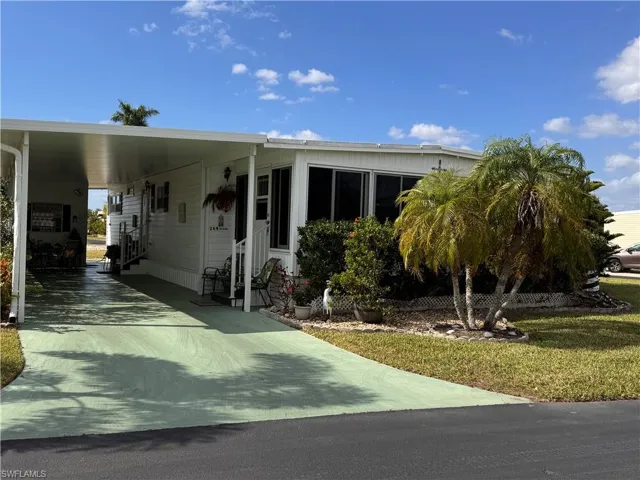Manufactured / mobile home featuring a front yard and a carport