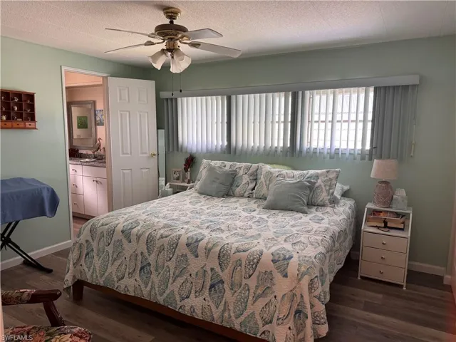 Master bedroom features ceiling fan, king bed, custom window treatments and laminate flooring
