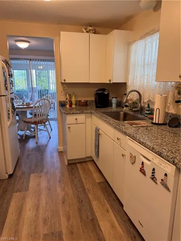 Kitchen with dishwasher, white cabinets, sink, dark hardwood / wood-style floors, and fridge
