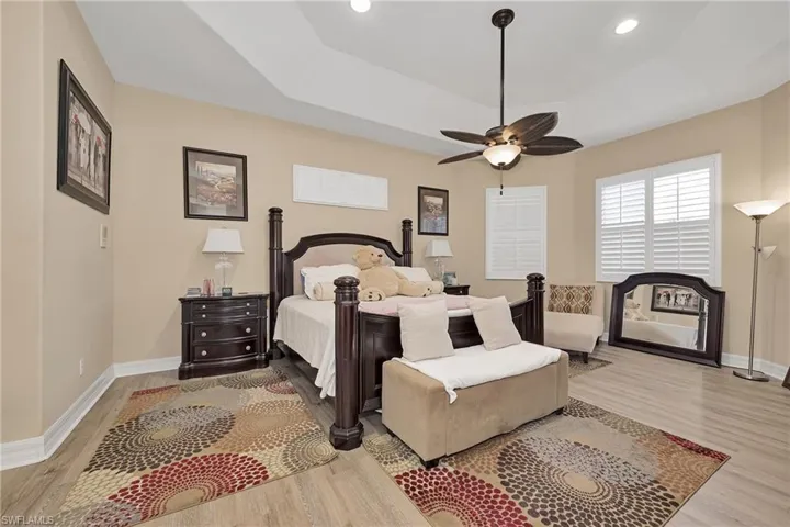 Bedroom with wood finished floors, a tray ceiling, recessed lighting, and ceiling fan