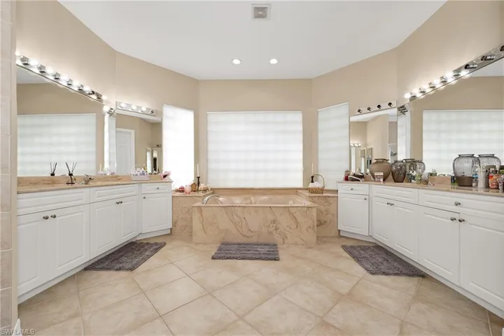 Full bathroom featuring tile patterned floors, a bath, two vanities, and recessed lighting