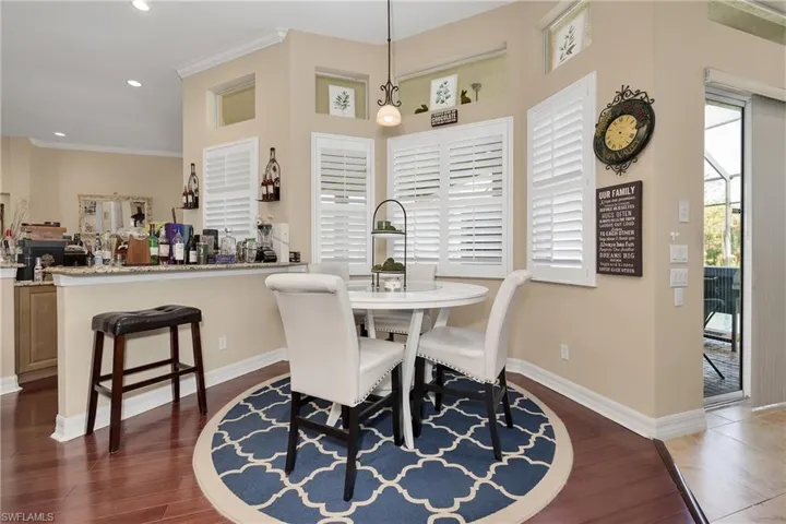 Dining area with dark wood-style flooring, crown molding, and recessed lighting
