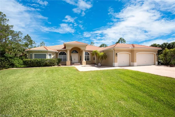 Mediterranean / spanish home with stucco siding, an attached garage, driveway, a front yard, and a tile roof
