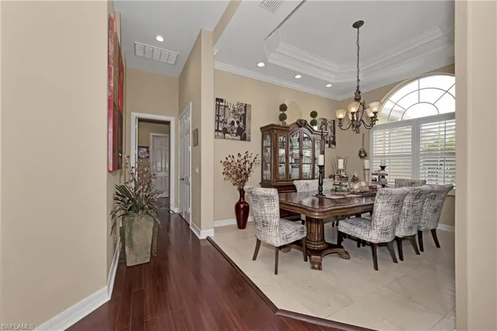 Dining space featuring a chandelier, recessed lighting, crown molding, a raised ceiling, and wood finished floors