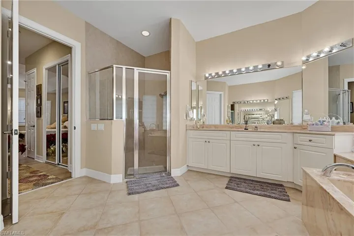 Bathroom with a shower stall, vanity, tile patterned flooring, and a bath