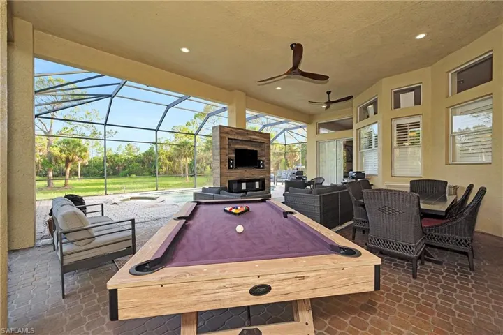 View of patio / terrace with an outdoor living space with a fireplace, a hot tub, glass enclosure, and ceiling fan