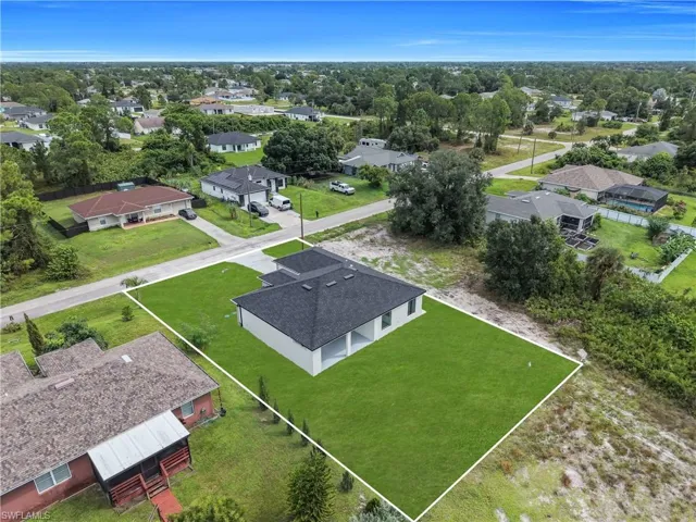 Newly constructed residence with a dark shingle roof, white exterior, and a manicured green lawn