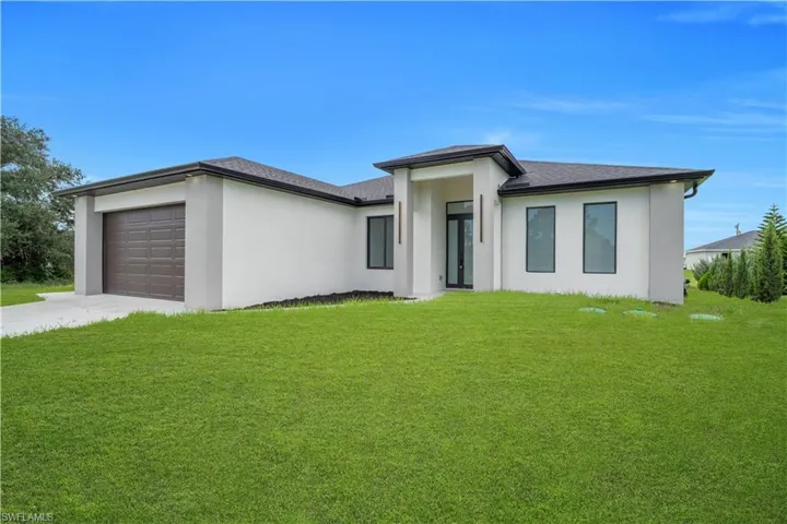 Modern stucco exterior with black-framed windows, a dark shingle roof, an attached garage with a dark wood-finish door, and a concrete driveway