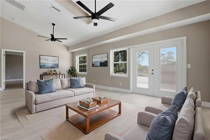 Virtually staged Spacious living area featuring light-toned flooring, neutral wall paint, and two modern ceiling fans