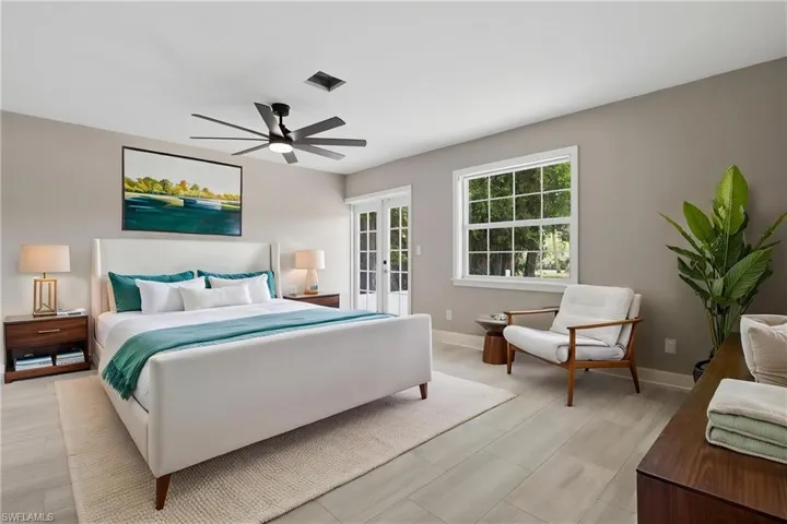 Virtually staged. This bedroom features light-toned flooring, a ceiling fan, and a large window with white trim