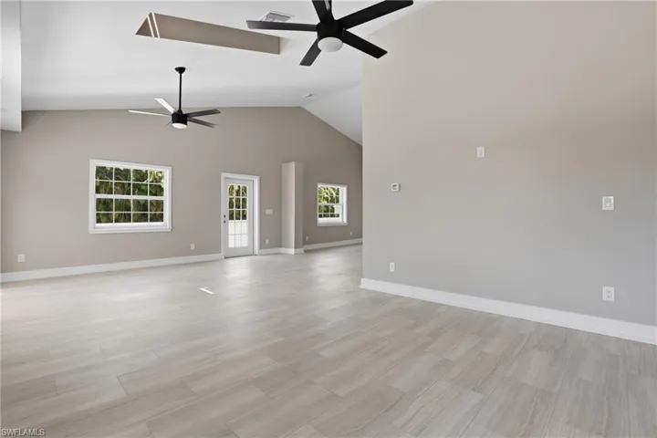 This expansive interior features vaulted ceilings with ceiling fans, light-toned tiled flooring, and neutral wall paint