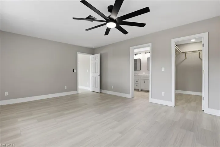 Spacious room featuring light-colored flooring, neutral-toned walls, and a modern ceiling fan