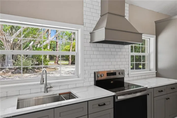 Kitchen featuring gray cabinetry, white countertops, white subway tile backsplash, and stainless steel appliances