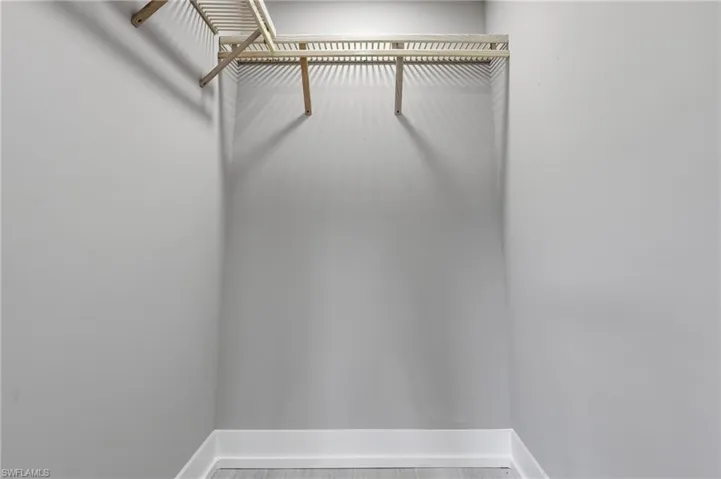 This closet features light gray walls, white baseboards, and a light-colored wooden shelving unit