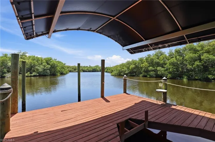 Private dock with a wood deck and a shaded canopy, offering views of the surrounding waterway and lush trees