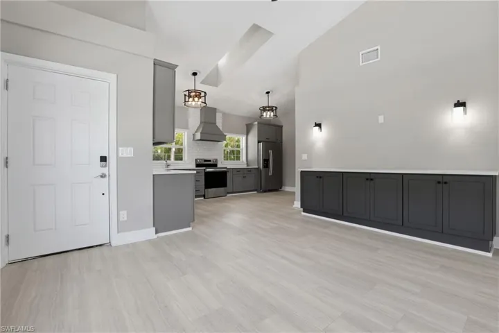 The open concept living area features light-toned flooring, a vaulted ceiling, and built-in dark gray cabinetry with a white countertop