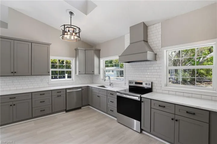 Kitchen featuring light wood flooring, gray cabinetry, white subway tile backsplash, and stainless steel appliances