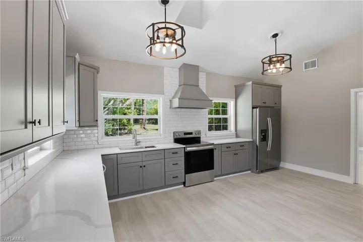 The kitchen features light gray cabinetry, white countertops, and a white subway tile backsplash