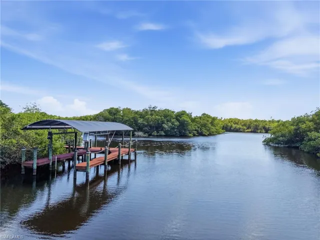 The property features a private covered dock with direct access to the water, surrounded by lush, mature trees