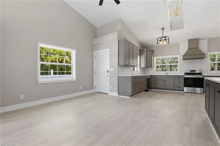 Open concept living space featuring a modern kitchen with gray cabinetry, white subway tile backsplash, and stainless steel appliances