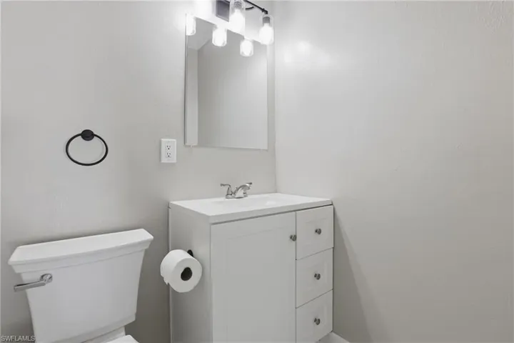 Bathroom featuring a modern white vanity with drawers, a wall-mounted mirror, and a contemporary light fixture