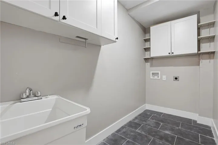The laundry room features white cabinetry, a utility sink, and tiled flooring