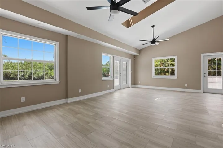 Spacious room with vaulted ceilings, recessed lighting, and two ceiling fans