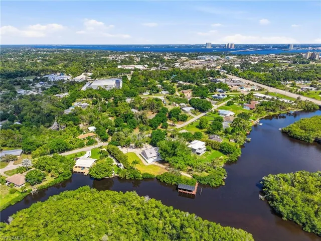 Aerial view showcasing the property's waterfront location, surrounded by green foliage