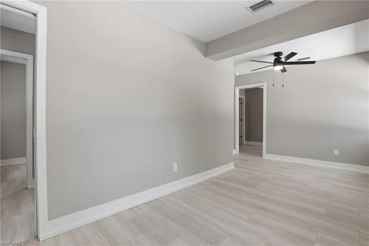 Spacious room featuring light-toned flooring, neutral walls, and a ceiling fan