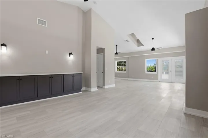 Spacious interior featuring light-toned tiled flooring, vaulted ceilings, and built-in cabinetry with a white countertop