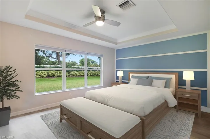 Bedroom featuring a tray ceiling, ceiling fan, and light wood-type flooring