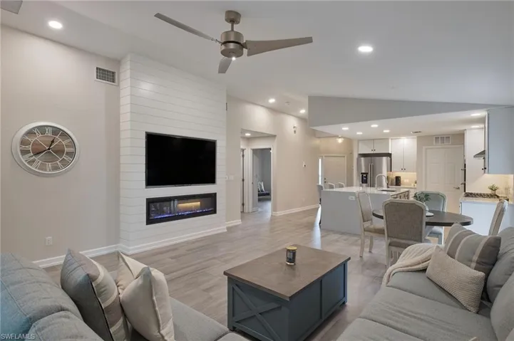Living room with light hardwood / wood-style flooring, sink, a fireplace, high vaulted ceiling, and ceiling fan