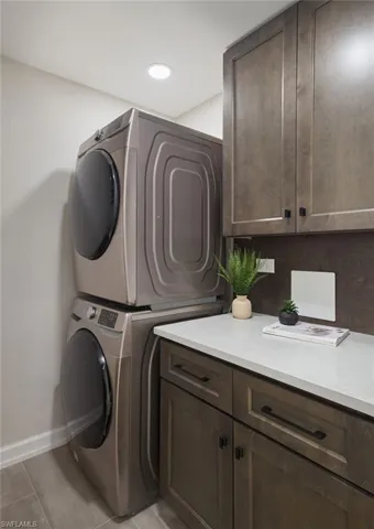 Laundry area with stacked washer / drying machine and cabinets