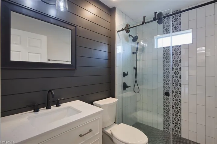 Bathroom featuring toilet, vanity, and walk in shower