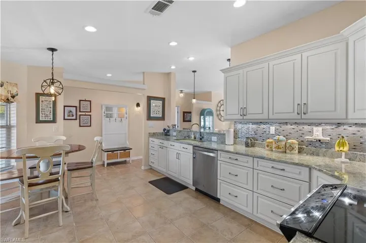 Kitchen featuring light stone counters, stainless steel dishwasher, black range with electric cooktop, tasteful backsplash, and decorative light fixtures