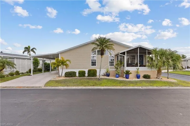 Manufactured / mobile home with an attached carport, a sunroom, driveway, and a front yard
