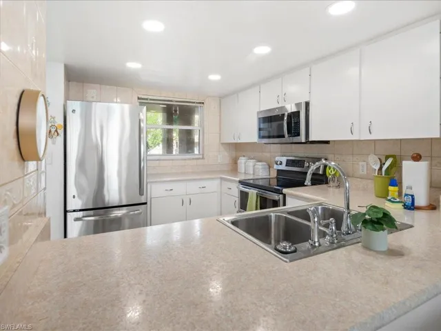 Kitchen featuring stainless steel appliances, light countertops, backsplash, recessed lighting, and white cabinets